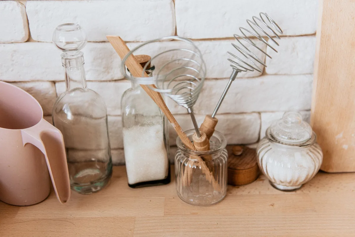 Glass jars and a whisk on a wooden counter
